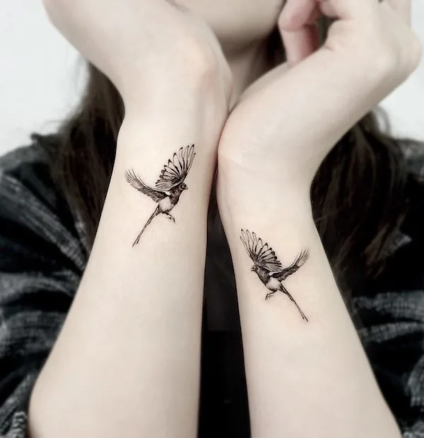 Matching bird tattoos on the side of the wrists
