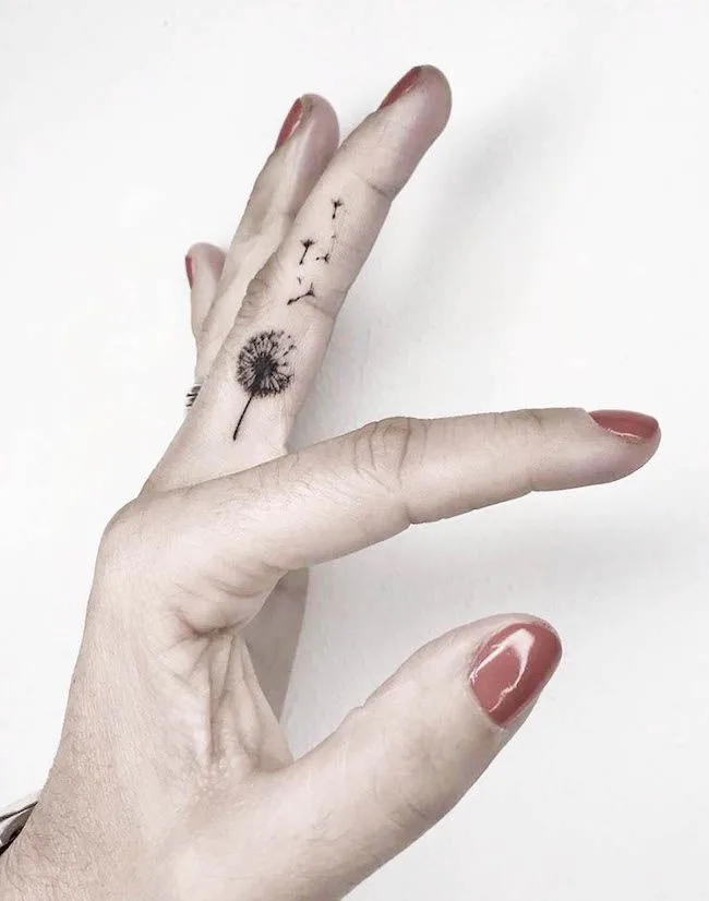 A detailed dandelion inner finger tattoo for women