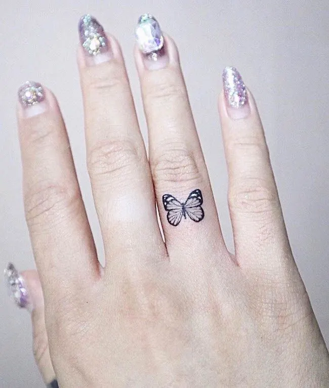 A small butterfly ring finger tattoo for women