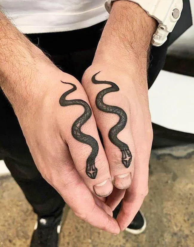 Bold snake tattoos on both thumbs