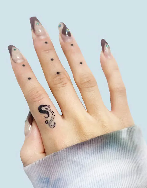 Tiny yin yang snakes finger tattoo.