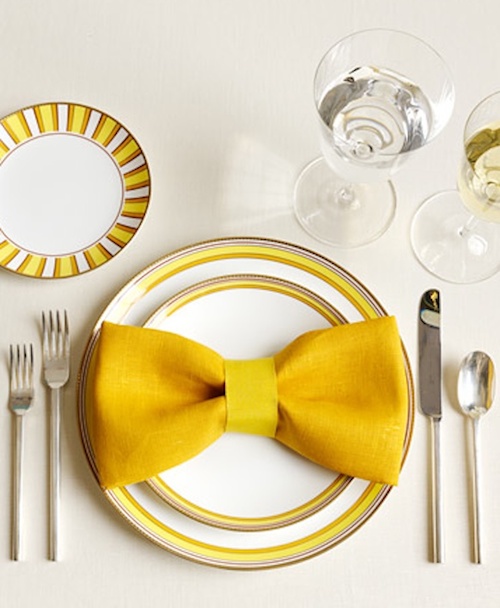 Bright yellow bow napkin folding for Christmas.